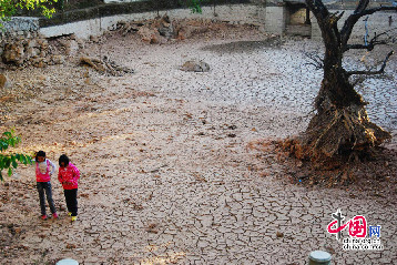两个女孩在干枯见底的黑龙潭中穿行而过。中国网图片库 俞方平 摄影。据悉，两三个月来，云南丽江古城没下过一场雨，致使丽江黑龙潭干枯见底。黑龙潭既是丽江古城的水源地，也是丽江文化的圣地。