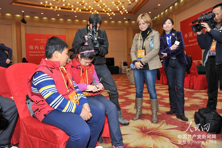 11月12日，在十八大新闻中心，两位来自《中国少年报》的小记者引起了在场中外大记者的关注。人民网记者 翁奇羽 摄