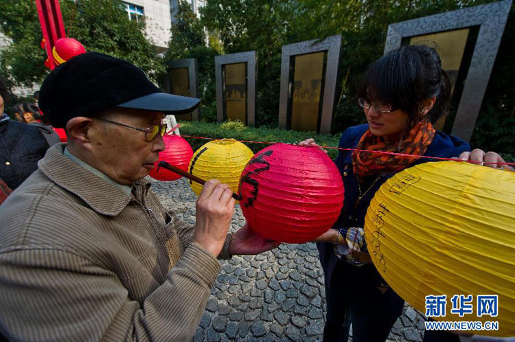 11月11日，70歲的秦咸宜老人（左）在燈籠上書寫“熱烈祝賀黨的十八大勝利召開”。