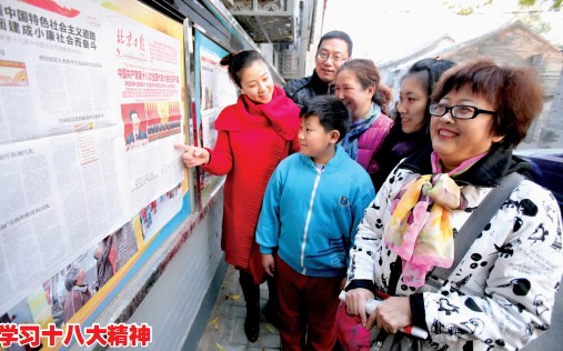街道机关干部与史家社区居民在胡同阅报栏前阅读近日发行的《北京日报》。 （文/摄 王延昕 杜欣）