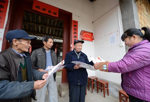 刘富祥（右二）在向当地村民发放简报（12月3日摄）。新华社记者周科 摄