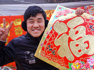 2013年1月31日，一名青年在山亭區李莊年集上展示剛買的鎦金 福 字。中國網圖片庫 劉明祥 攝影。 