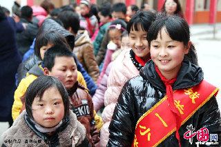 2013年3月1日，河南省宝丰县城关一小焦洁学雷锋活动小组的同学（右）一对一拉着特殊儿童的手前往活动室。中国网图片库 何五昌摄