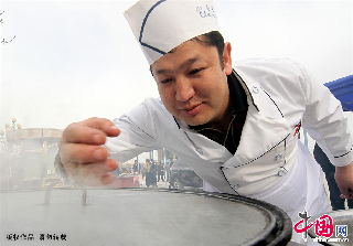 一位厨师在嗅抓饭的香味判断抓饭的成熟情况。 中国网图片库/蔡增乐 摄