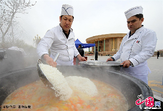 两位厨师正在往锅里下米。 中国网图片库/蔡增乐 摄