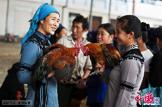两位手持公鸡的村民在交流。　中国网图片库/郑跃芳 摄