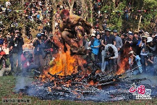 2013年3月14日，云南弥勒县，红万村祭火节，纹身蒙面的小伙子身上涂满了泥巴，纵情越过熊熊燃烧的篝火。中国网图片库 何东平摄