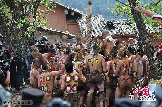 2013年3月14日，雲南彌勒縣，紅萬村祭火節，龍樹下，紋身蒙面的小夥子們圍著“畢摩”巫師鑽木取火。中國網圖片庫 何東平攝