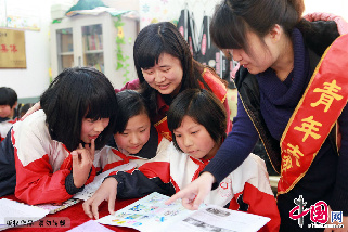 4月11日，在安徽宿州市桃园镇邱寨希望小学留守儿童“光明驿站”，志愿者为学生讲解少年读物“蓝天”。中国网图片库 马勇 摄