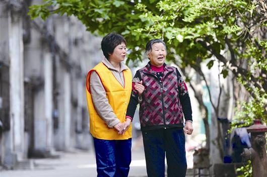  图为：护理人员为老人提供陪伴散步服务