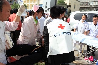 四川省雅安市芦山县发生7.0级地震后，紧急救援工作随即展开。图为医务人员及红十字志愿者紧急救助地震受伤人员。  杨文强/中国网图片库