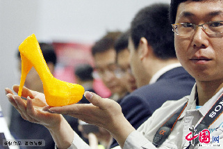 2013年4月25日，第六屆中國留學人員南京國際交流與合作大會在南京國際博覽中心舉行，大會現場展示的一款由3D印表機列印出來的塑膠高跟鞋讓參觀者大飽眼福。圖為工作人員在展示3D印表機列印出來的高跟鞋。中國網圖片庫 董金林 攝