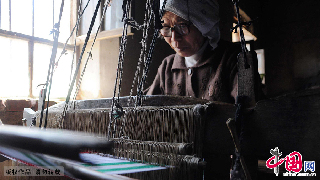 孫之榮在使用傳統四匹繒織布機紡織老粗布。　中國網圖片庫/張濱濱 攝