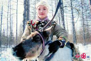 敖魯古雅鄉的牧民達瓦，在大森林的家中女兒身著鄂溫克民族服裝與一頭馴鹿在一起。中國網圖片庫 王偉/攝