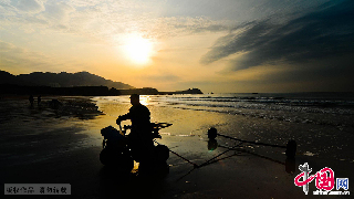 一位騎著四輪摩托的漁民的海邊剪影。　中國網圖片庫/王海濱 攝