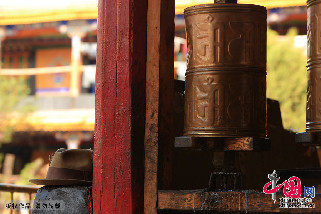 一位手中拿著一串佛珠身著傳統藏族服飾的老人走了進來，摘下了左右兩側各有一根短羽毛的帽子放在墻角，轉身順時針撥轉了旁邊的四個小轉經筒，走向屋內的大轉經筒。中國網記者 楊佳攝影 