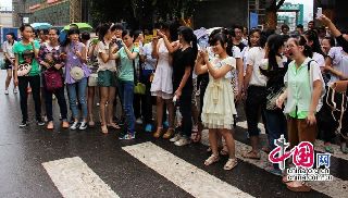  6月8日下午，四川宜宾市一中考点外，一名帅气的交警站在公路中间指挥执勤，因为帅气的形象，挺直的身躯，标准的指挥手势，引来参加高考的众多女生围观，纷纷拿出手机相机争先拍照合影。