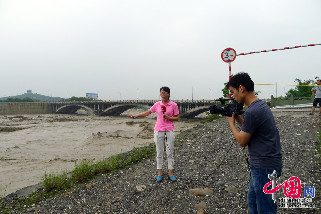 7月9日，四川绵阳江油市绵江公路(绵阳至江油)通口河老青莲大桥，因暴雨形成的特大洪峰冲击发生垮塌。图为记者在现场采访。中国网图片库 李晓平摄影  