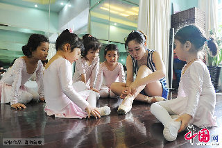 女孩子们正在看老师张馨滢穿上芭蕾舞鞋。跟这群孩子一样，90后女孩张馨滢也是从小泡在舞蹈训练房中的。  中国网图片库 赖鑫琳 /摄