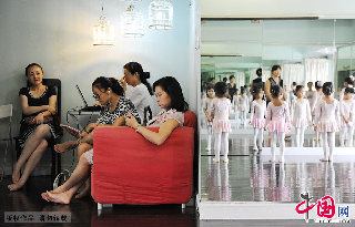 家長們在舞蹈房中等待跳舞的孩子,身後練功房的鏡子裏映射出孩子們的身軀，柔弱卻堅忍，用足尖認真書寫別樣的童年。  中國網圖片庫 賴鑫琳/攝