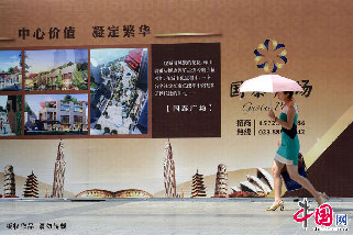 一位女士在烈日高温中从广告牌前经过。 中国网图片库 钟桂林摄