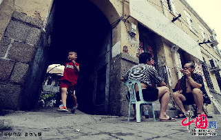 2013年7月14日，青島。老街上，兩位老青島在石板路上聊天，剛好一名男孩從裏院跑出。中國網圖片庫 王海濱攝影