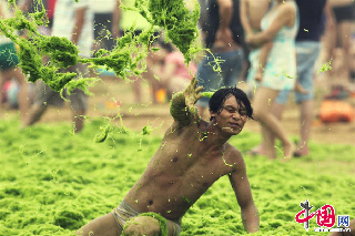 2013年7月18日，遊客扎堆戲海灘，滸苔染身似外星人。  中國網圖片庫 王海濱 攝影