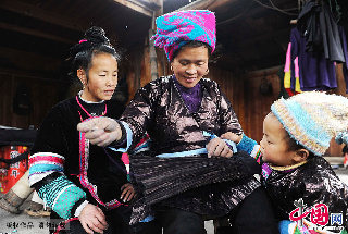 一名侗族妇女在用针线缝制围裙。    中国网图片库  赖鑫琳  摄