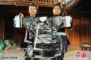 两名侗族妇女在展示一件侗衣成品。   中国网图片库  赖鑫琳  摄