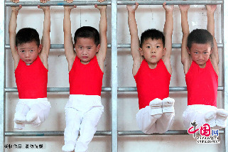 7月30日，在安徽省亳州市文帝东路亳州体操训练基地体操馆内，孩子们正在教练的指导下强化训练。图为受训的小队员在利用墙边的器械进行练习，从孩子们的表情上可以看出训练相当艰苦。 中国网图片库 刘勤利摄