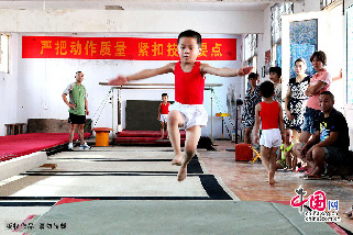 7月30日，在安徽省亳州市文帝东路亳州体操训练基地体操馆内，孩子们正在教练的指导下强化训练。图为小队员在海绵垫上进行训练。中国网图片库 刘勤利摄