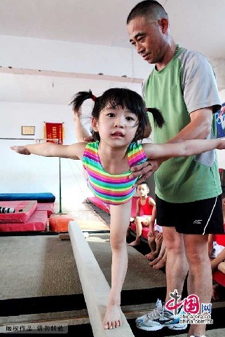 7月30日，在安徽省亳州市文帝东路亳州体操训练基地体操馆内，孩子们正在教练的指导下强化训练。图为正在艰苦训练的小队员，虽然训练很艰苦，但还是从小队员的表情中看到了他们的执着。中国网图片库 刘勤利摄