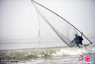  一位漁民在海浪中踩著高蹺捕撈小蝦。幾米深的海水中，捕蝦人踩著高蹺推著蝦網，需承受幾十斤甚至上百斤的阻力，其艱辛可想而知。  中國網圖片庫 陳為峰/攝