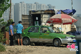 2013年08月04日，四川省成都市，一辆出租车在路边加注甲醇，背后一辆废弃货车改装的货箱里存放着甲醇。图片来源：成都商报/CFP