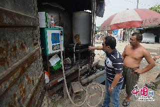 2013年08月05日，四川省成都市，当着老板陈家华（右）的面执法人员打开货厢后发现甲醇加注和计价装置一应俱全。图片来源：成都商报/CFP