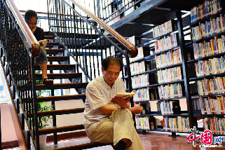 2013年8月11日，杭州气温再次突破40℃，这已是连续7天出现40℃以上的极端高温天气，杭州图书馆成为市民学习纳凉的好去处。图为市民在杭州图书馆里看书纳凉。   中国网图片库 龙巍摄影