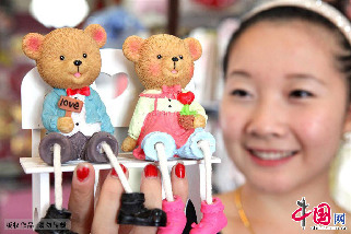 8月11日，一位女孩在安徽省亳州市区一家情侣饰品店铺展示情人节饰品。中国网图片库 刘勤利摄