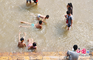 吉林松花江水位上涨，亲水长廊变身游泳池。图为2013年8月12日，在吉林省吉林市松花江畔，一些孩子把亲水长廊当成游泳池，在江水中嬉戏玩耍。摄影：中国网图片库 王明铭