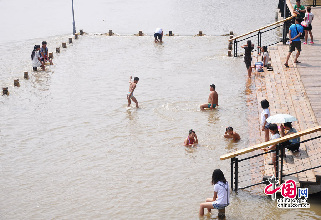 吉林松花江水位上涨，亲水长廊变身游泳池。图为2013年8月12日，在吉林省吉林市松花江畔，市民和孩子在上涨的江水中嬉戏玩耍。摄影：中国网图片库 王明铭