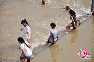 吉林松花江水位上涨，亲水长廊变身游泳池。图为2013年8月12日，在吉林省吉林市松花江畔，市民坐在上涨的江水中休憩。摄影：中国网图片库 王明铭