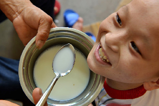 2013年8月14日，义乌市赤岸镇尚阳村爱心妈妈毛菊云，对收养在家里的残疾孩子一口口地喂牛奶。中国网图片库 张建成摄