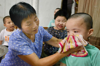 2013年8月14日，义乌市赤岸镇尚阳村爱心妈妈毛菊云，精心料理收养在家里的残疾孩子。中国网图片库 张建成摄
