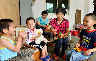 2013年8月14日，义乌市赤岸镇尚阳村爱心妈妈毛六妹，陪收养在家里的6个孩子玩。中国网图片库 张建成摄