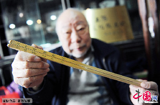 蓝翔在展示自己的藏品，这是一双刻有对联的老竹筷。  中国网图片库 赖鑫琳/摄