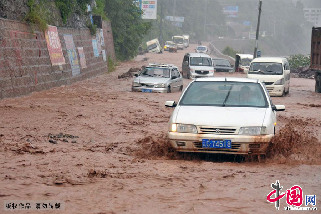 8月25日下午，云南彝良县城朱家沙坝处因暴雨引发山洪和泥石流灾害，公路上洪水和淤泥已可淹没轿车车轮，一辆轿车正在洪水和泥石流中疾行。中国网图片库 彭洪摄