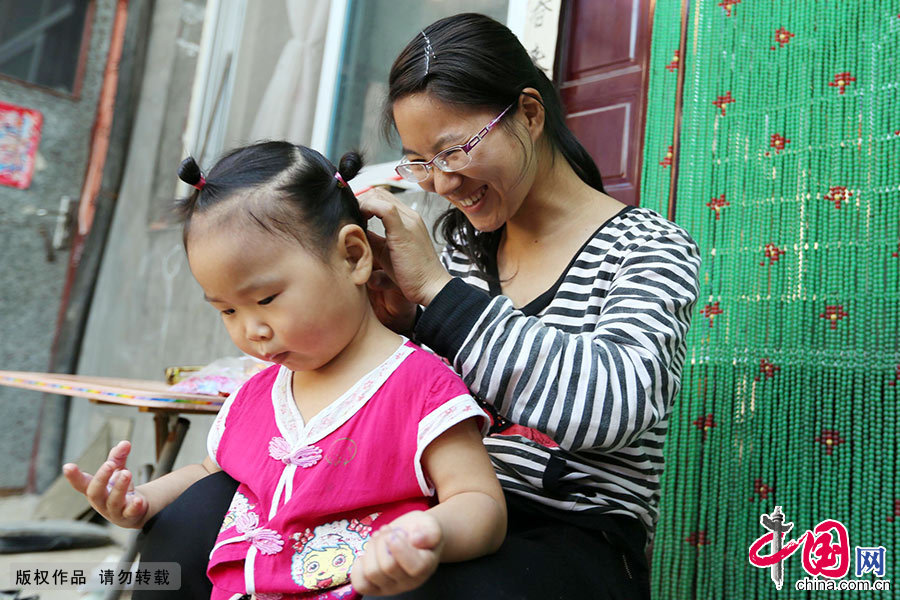 两岁半的女儿傅梓琦睡醒了，付慧珍给女儿梳头绑辫子。 中国网图片库 毕兴世/摄