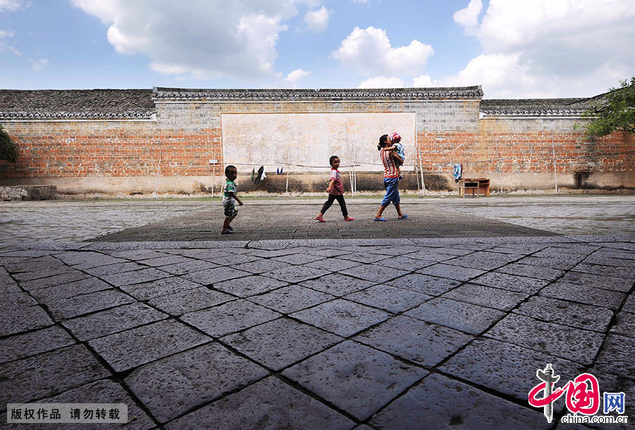 一名居住在圍屋內的婦女領著孩子從圍屋的祠堂門前經過。 中國網圖片庫 賴鑫琳/攝
