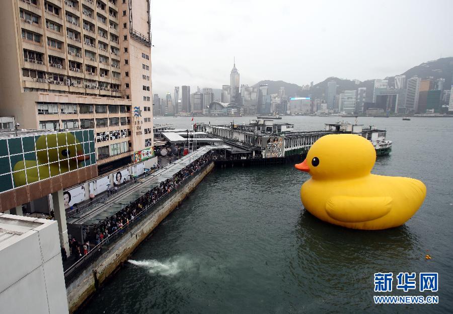  5月22日，游客在香港尖沙咀观赏巨型橡皮鸭。由荷兰艺术家霍夫曼创作的巨型橡皮鸭在经过数日的检查和维修之后，5月21日晚间充气，22日在尖沙咀正式亮相，吸引大量市民和游客冒雨前来参观。新华社发（王雨清摄）