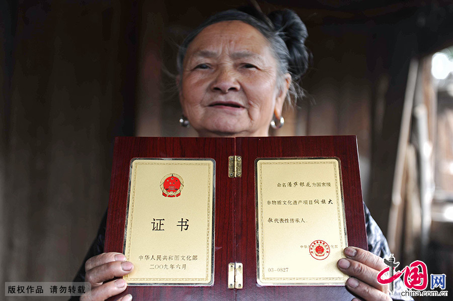 潘萨银花在展示文化部为其颁发的国家级非物质文化遗产证书。她是小黄村唯一一名侗族大歌的代表传承人。中国网图片库 赖鑫琳/摄 