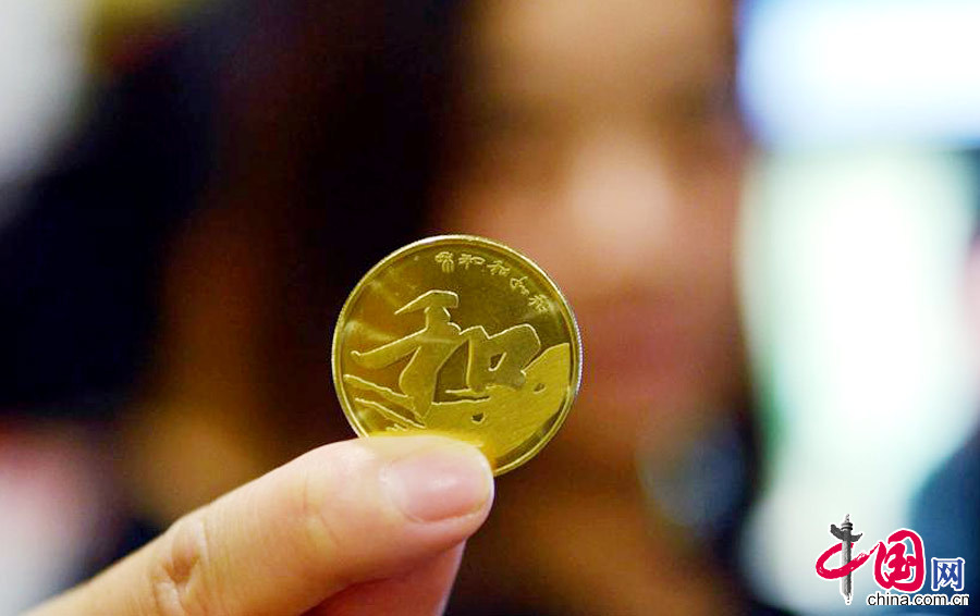  2013年09月23日，浙江省杭州市，一位顾客在杭州某银行里展示“和”字书法---行书普通纪念币。中国网图片库 龙巍摄影